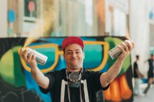 Graffiti artist yukuka, spraying colours into the air facing camera