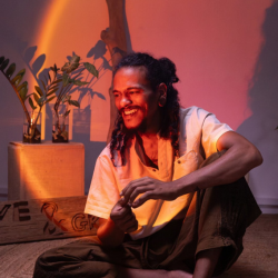 Nabi Mauritian artist, local artist posing for photos, smiling, looking away, sun set lamp and warm light, singer composer in mauritius, connect your flow